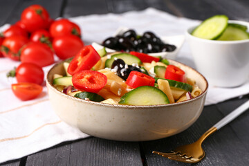Bowl with tasty pasta salad on dark wooden background