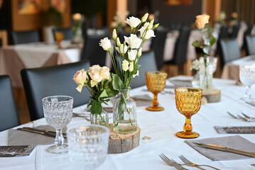 On the banquet table there are plates with napkins glasses and cutlery