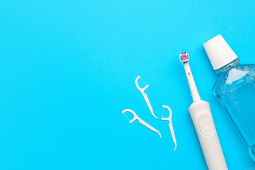 Floss toothpicks, electric brush, paste and rinse on blue background