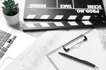 Fototapeta premium Clipboard with storyboard, laptop and movie clapper on grunge background, closeup
