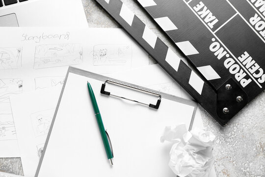 Clipboard with storyboard, laptop and movie clapper on grunge background