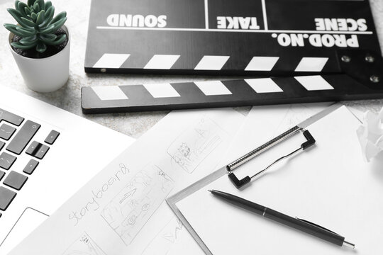 Clipboard with storyboard, laptop and movie clapper on grunge background, closeup