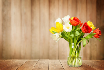 bouquet of tulips in a vase on a wooden background with copy space