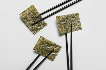 Chopsticks with nori sheets on white background