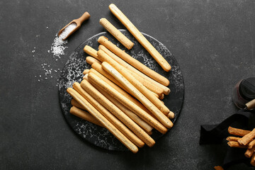 Slate board with tasty Italian Grissini on dark background