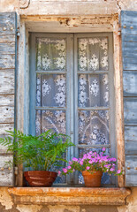 Fototapeta na wymiar Fenster mit Blumentöpfen und blauen Fensterläden