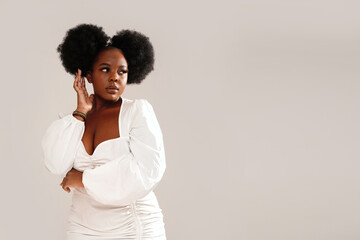 Beauty portrait of attractive woman with afro hairstyle and delicate makeup looking away, posing over studio background.