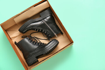 Cardboard box with stylish shoes on turquoise background