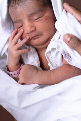 Fototapeta na wymiar Cute little newborn baby curled up sleeping in hand on a white blanket at hospital