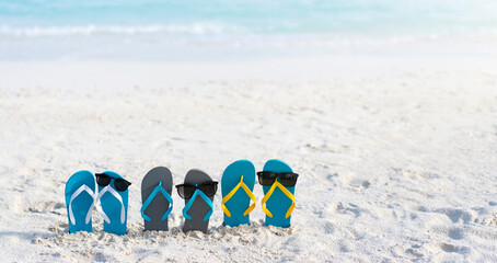 Three pairs of flip flops on the beach on the background of ocean in the Maldives. Family vacation