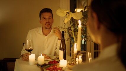 Positive man speaking at candles room closeup. Newlyweds having romantic date