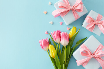 Flat lay composition of gift boxes with bows bouquet of flowers colorful tulips hearts baubles on isolated pastel blue background with empty space. Happy Mother's Day concept