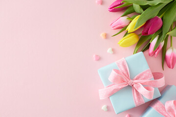 Top view composition of gift boxes with bows bouquet of flowers yellow pink tulips colorful hearts on isolated pastel pink background with copyspace. Happy Mother's Day concept