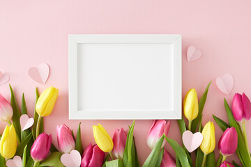 Mother's Day concept. Creative layout made of white photo frame origami paper hearts yellow pink tulips flowers on isolated pastel pink background. Flat lay blank space