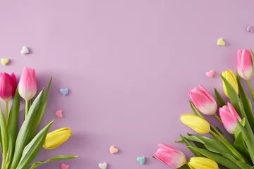 Tuinposter Mother's Day atmosphere idea. Top view composition of bouquets of pink yellow tulips flowers and colorful hearts baubles on isolated light violet background with copyspace © Goncharuk film
