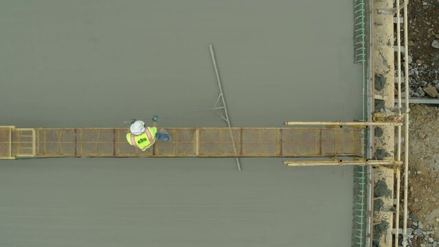 Aerial: Drone Top Panning Shot Of Male Architect Spreading Concrete On Under Development Bridge - Tuscaloosa, Alabama