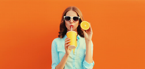 Summer portrait of happy young woman drinking fresh juice with slice of orange fruits on background