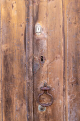 A rusted metal pull on an old wooden door.