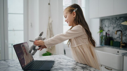 Cute baby showing toy to laptop screen cozy home closeup. Positive girl talking