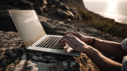 A close up of a person working on their laptop outside remotely near the sea.