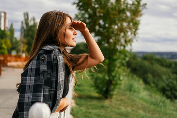 Obraz premium Romantic young woman is looking far while making shadow with her hand above eyes.