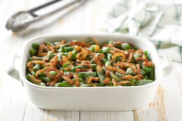 Green bean casserole sprinkled with crispy fried onions served on ceramic cooking baking dish.  Healthy summer veggie food.
