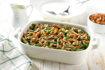 Roasted green bean with crispy fried onions served in a ceramic form on a wooden table. Healthy root vegetables concept.