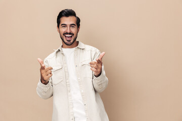 Fototapeta na wymiar Portrait of a stylish man smile shows a class sign thumb up on a beige background in a white t-shirt, fashionable clothing style, copy space