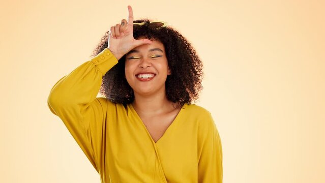 Portrait, funny face and loser with a black woman in studio on a yellow background making fun. Hand gesture, rude and comic with an attractive young female showing a sign or symbol of comedy