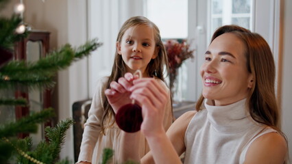 Smiling woman hanging xmas toy at branch portrait. Overjoyed baby clapping hands