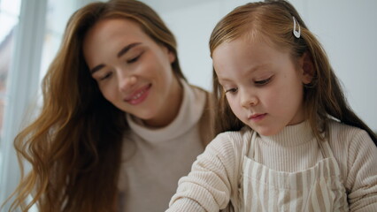 Loving mother kissing child kitchen portrait. Smiling woman embracing daughter