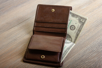 Leather open brown wallet with banknote on wooden table