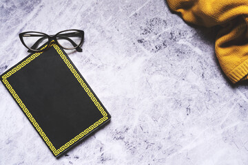 Minimalismo elegante: Un libro negro y accesorios sobre una mesa de mármol