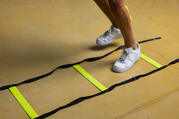 Close up of feet training on agility ladder drills on floor at gym during Fitness class cardio...