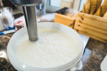 Close shot of milk in a white container being mixed with blender for ice cream. High quality photo