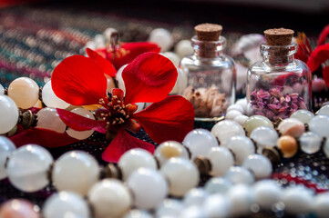Obraz na płótnie Canvas Quince petals and pearl necklace and tiny glass bottles on a textile background. Romantic concept. Alternative medicine, aromatherapy or esoteric background.