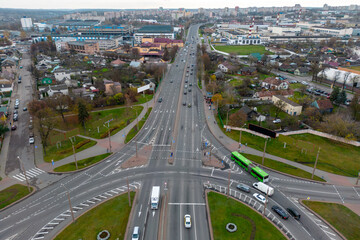 Top view of a major road junction in the city during the day. A large busy roundabout. Urban traffic and infrastructure.  Green spaces inside the intersection.
