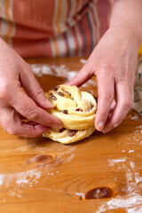 hands of the baker in the home kitchen are preparing rich buns with raisins. close-up, selective focus.