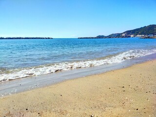 日本の和歌山県の観光地、快水浴百選海の部特選にも選ばれた片男波海水浴場の砂浜の波打ち際の夏の風景（コピースペースあり）