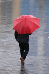 Man with red umbrella under rain walking from back part and no face. Rain autumn concept. Selective focus.