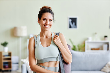 Waist up portrait of smiling woman wearing sportswear looking at camera ready for home workout, copy space