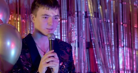 Standup comedy show. Close up portrait of young male stand-up performer speaks into the microphone. 
