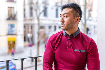 Fototapeta premium Portrait of a Chinese young man on a balcony at home, everyday situation, apartment