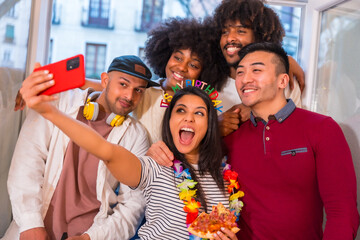 Portrait of a group of friends eating pizza on the terrace at home on a birthday, taking a souvenir selfie