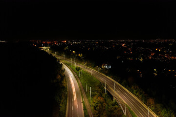 Fototapeta na wymiar Top down view to road. Romantic night aerial photo of cars traveling. The light on the road at night in city. Background scenic road drone view. Tram railways background