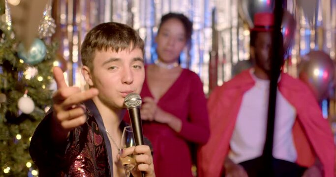 Portrait of young man showing obscene hand gesture, looking at camera during New Year celebration. A movement of hands, that is considered exceedingly offensive or vulgar in some particular cultures. 