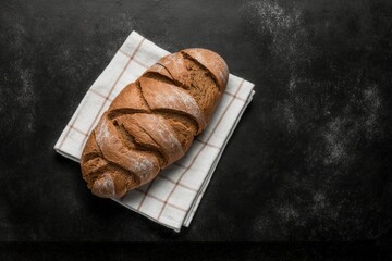 Delicious freshly baked bread on top of a tea towel on the black stone table, a photo that will make your mouth water