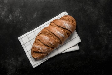 photo of freshly baked crusty bread, placed on a delicate tea towel, on a sturdy black stone table