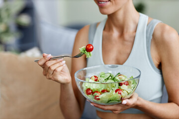 Closeup of woman eating fresh salad while enjoying healthy lifestyle and organic food at home