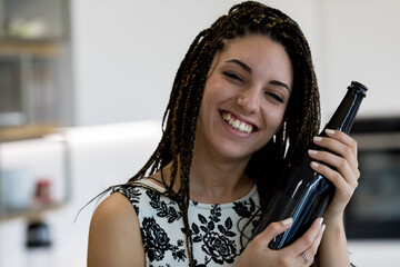 Enthusiastic girl presents dark wine bottle, traditional accompa